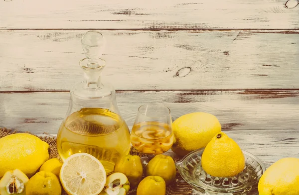 Ahşap masa üzerinde cam şişede meyve likörü. Ayva ve limon tentür ev yapımı.