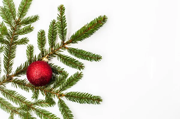 Weihnachtsbaum mit Christbaumkugel auf weißem Hintergrund. rote Glaskugel auf Fichte, Draufsicht. — Stockfoto