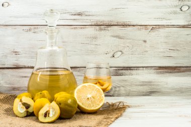Bir cam şişe rustik ahşap masa üzerinde meyve likörü. Limon ve ayva meyvelerden yapılmış ev yapımı alkol