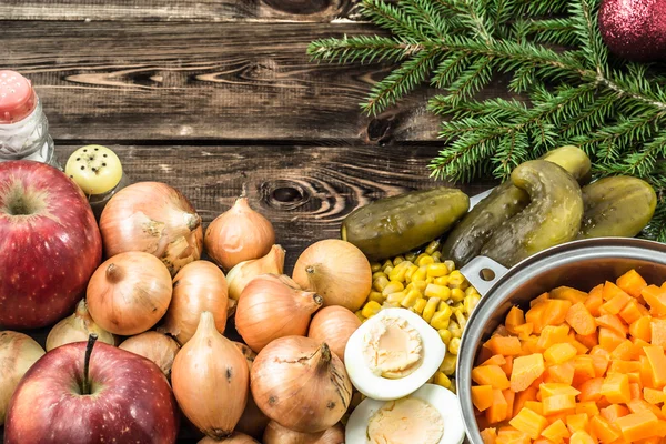 Ingredientes de ensalada de verduras y rama de árbol de Navidad con adorno rojo en la mesa de madera — Foto de Stock