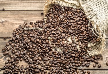 Çuvala ahşap masa üzerinde siyah kahve çekirdekleri