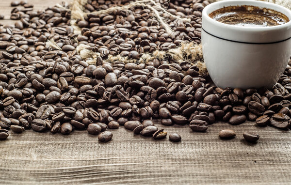 Cup of coffee and coffee beans on wooden table, overhead