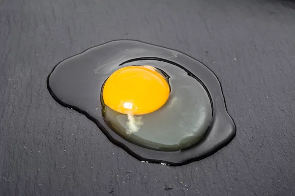 Raw egg spilled on black board, top view, cooking concept — Stock Photo, Image