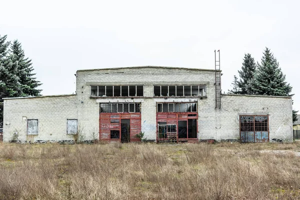 Industriebrache, alte Fabrikwand aus weißen Ziegeln mit beschädigten Türen und Fenstern — Stockfoto