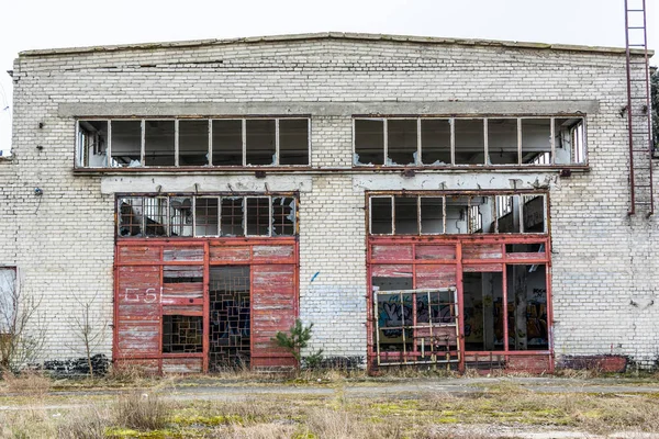 Industriebrache, alte Fabrikwand aus weißen Ziegeln mit beschädigten Türen und Fenstern — Stockfoto