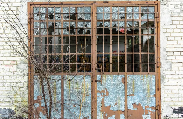 Parede de fábrica industrial velha de tijolos brancos com porta danificada e janelas — Fotografia de Stock