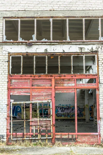 Industriebrache, alte Fabrikwand aus weißen Ziegeln mit beschädigten Türen und Fenstern — Stockfoto