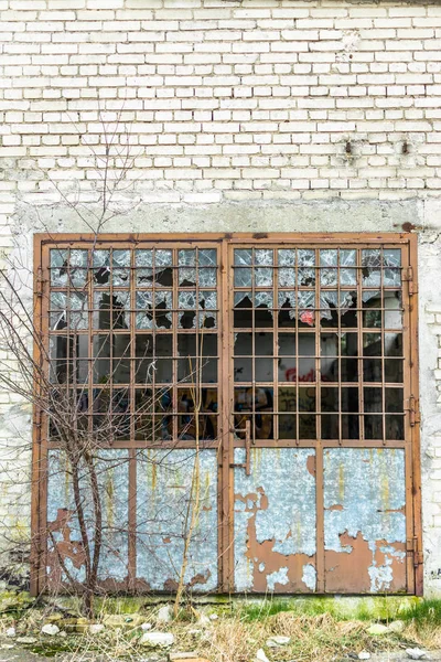 Parede de fábrica industrial velha de tijolos brancos com porta danificada e janelas — Fotografia de Stock