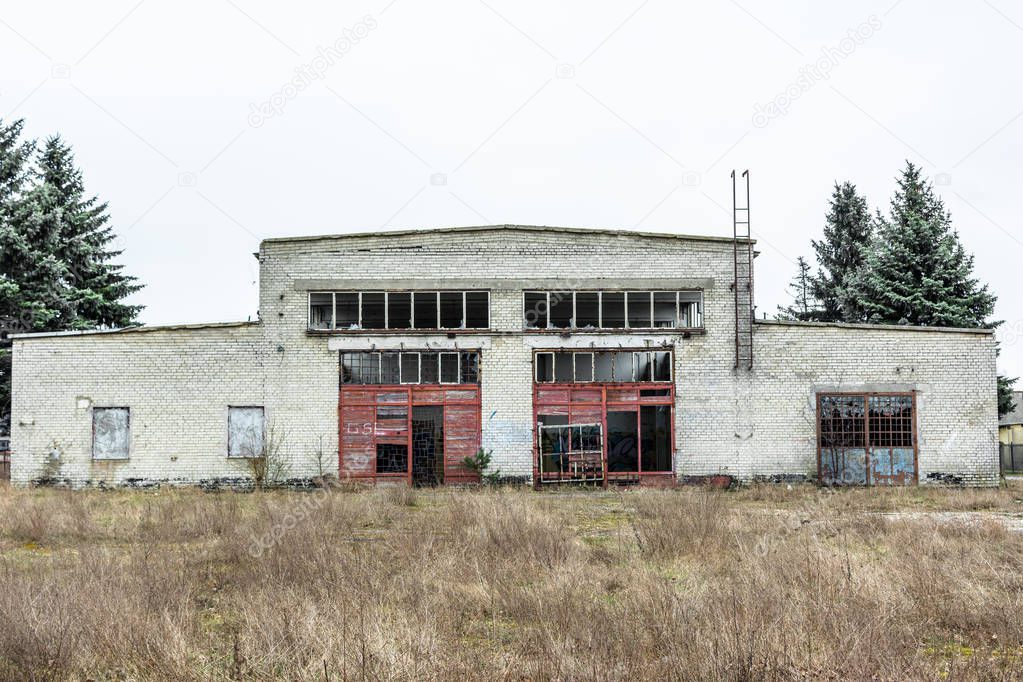 Abandoned industry, old industrial factory wall of white bricks with damaged door and windows