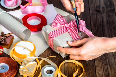 Noel hediyesi eski kağıt ve kurdeleler ile kaydırma. Eller hediye yay yapma.