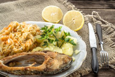 Kızarmış balık, patates ve lahana turşusu rustik zemin üzerine haşlanmış. Geleneksel Lehçe akşam yemeği.