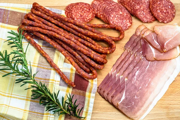 Surtido de carnes: kabanos, rebanadas de jamón salami sobre madera — Foto de Stock