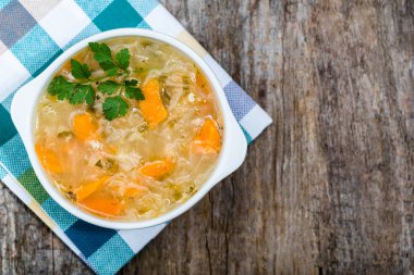 Rustik ahşap masa üzerinde bir kasede ek yükü sebze çorbası