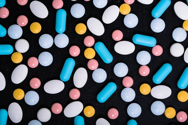 Bunte Arzneimittel. Tabletten, Pillen auf schwarzem Hintergrund. Arzneimittel und Medikamente. — Stockfoto