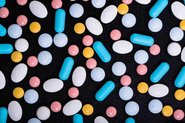 Colorful medicines. Tablets, pills on black background. Pharmaceutical drugs and medications.