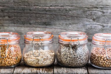Sağlıklı vegan gıda, tohum ve tahıl rustik masa, nohut, bezelye, ayçiçeği tohumu, yulaf ezmesi olarak kavanozlara