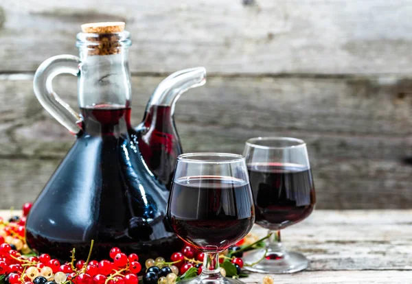 Стеклянная бутылка вина на деревянном столе. Сладкий алкоголь из фруктов много различных ягод смородины — стоковое фото