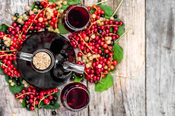 Bouteille de vin sur table en bois. Alcool sucré à base de fruits de nombreuses variétés de groseilles — Photo