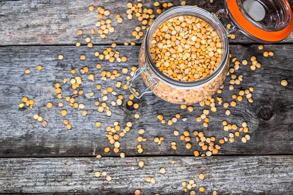 Pois cassés, pois dans un bocal rustique sur une table en bois, ingrédients végétaliens sains — Photo