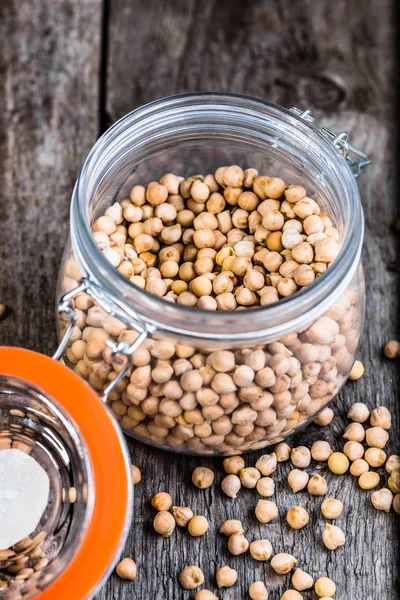 Raw chickpeas in rustic jar on wooden table, healthy eating, vegan diet concept — Stock Photo, Image