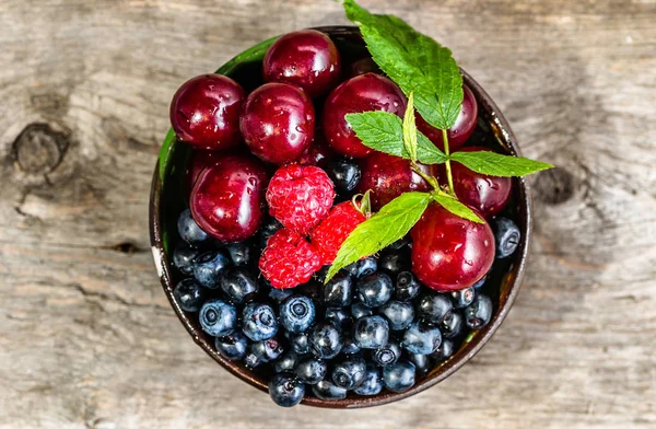 Літні фрукти в мисці на сільському столі, концепція здорового харчування, вид зверху, крупним планом — стокове фото