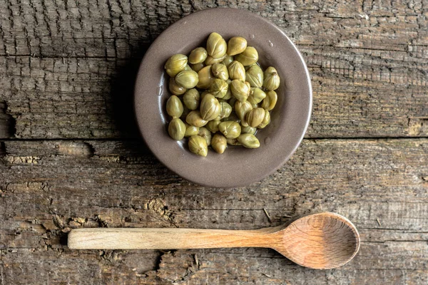 Capperi marinati, ingredienti della cucina italiana su tavola di legno — Foto Stock