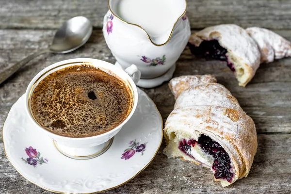 Вкусный десерт - круассан с мармеладом и чашкой кофе на деревянном столе — стоковое фото