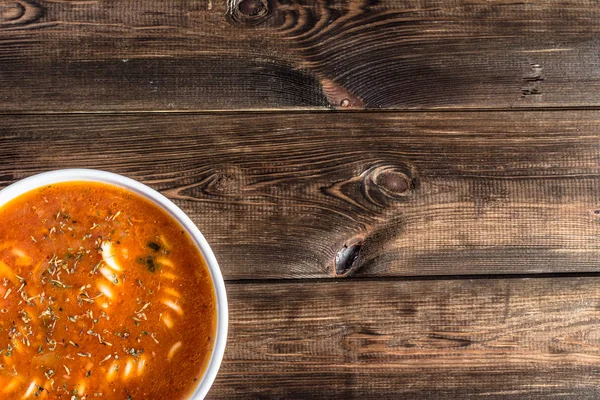 Sopa de tomate cocido con fideos en una mesa de madera, tamaño de la porción en un tazón, vista superior, espacio para copiar — Foto de Stock