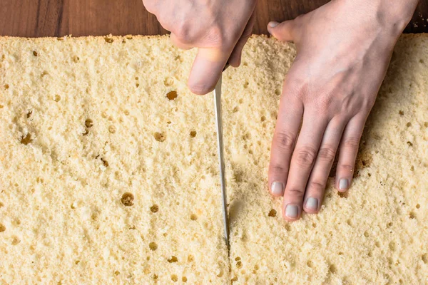 Cutting sponge cake on layers. Preparing a torte cake, detail of hands and knife, baking concept — Stock Photo, Image