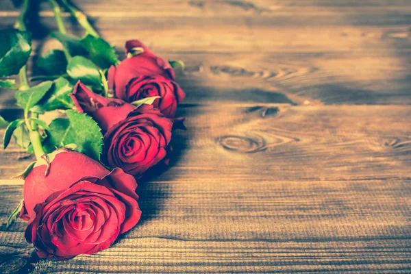 Fiori giorno delle donne, cornice con rose rosse su sfondo rustico in legno — Foto Stock