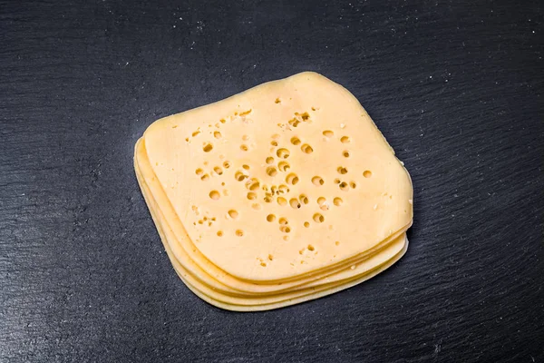 Rebanadas de queso amarillo sobre fondo negro — Foto de Stock