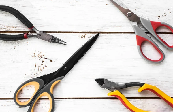 Pincers and scissors tools on wood background