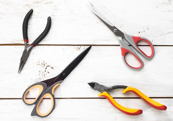 Pliers and scissors tools on wood background