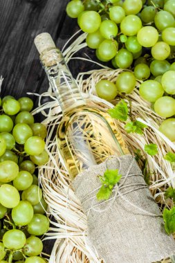 Yeşil üzüm gelen beyaz şarap şişesi. Yaşlı ahşap kiler içinde ev yapımı şarap.