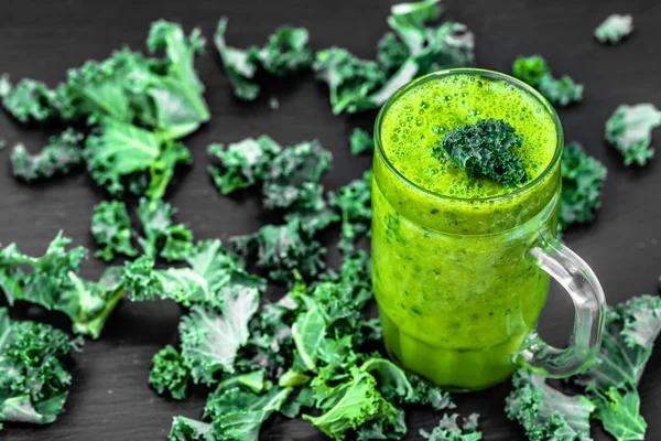 Vegetable smoothie with green kale leaves in a glass on black background — Stock Photo, Image