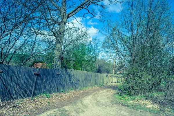 Rural road and wooden fence, spring landscape with countryside scene