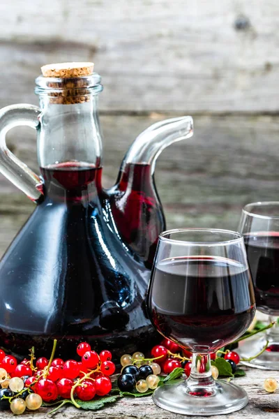 Old wine carafe on wooden table. Sweet alcohol made from fruits many variety berries currant