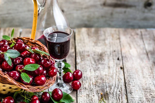 Vin de cerise dans une bouteille en verre sur une table en bois. Alcool sucré à base de cerises — Photo