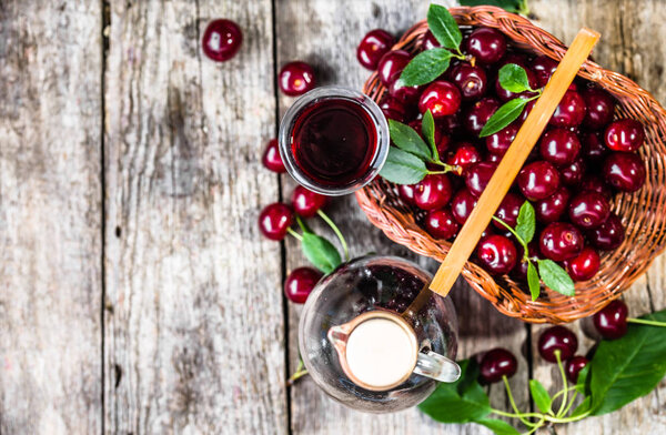 Glass of alcohol tincture made from cherry fruits, liquor in a bottle on rustic background