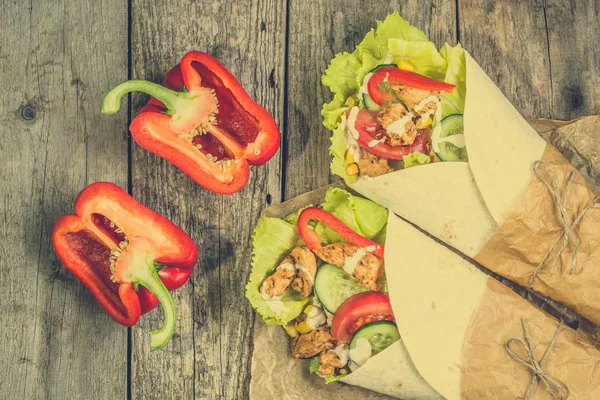 Burritos mexicanos, envolturas de tortilla rellenas de verduras frescas y pollo a la parrilla sobre una mesa rústica — Foto de Stock