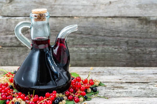 Vieille carafe de vin sur table en bois. Alcool sucré à base de fruits de nombreuses variétés de groseilles — Photo