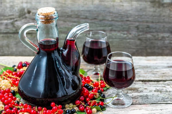 Ahşap masa üzerinde eski şarap sürahi. Tatlı alkol yapılmış birçok çeşitli meyveler Frenk üzümü meyve