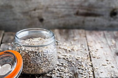 Ahşap masa, madde yemek sağlıklı vegan üzerinde rustik kavanoza soyulmuş ayçiçeği tohumu