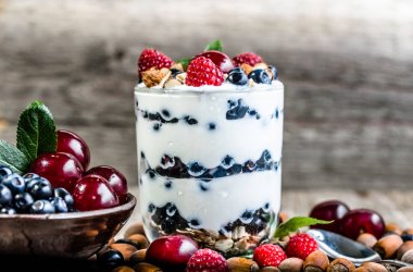 Soğuk yoğurt dondurma ile meyve ve fındık bir cam fincan, kiraz, ahududu ve yaban mersini, yaz tatlı kavramı ile dondurulmuş dondurma