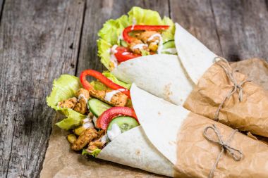 Meksika fajitas, tortilla saran taze sebze ile dolu ve rustik ahşap masa üzerinde tavuk ızgara