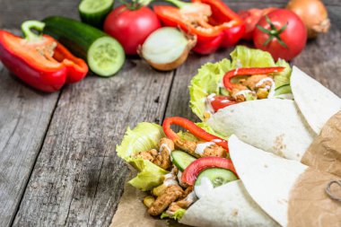 Meksika burrito, tortilla saran taze sebze ile dolu ve rustik masa üzerinde tavuk ızgara