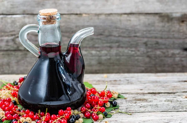 Vieille carafe de vin sur table en bois. Alcool sucré à base de fruits de nombreuses variétés de groseilles — Photo