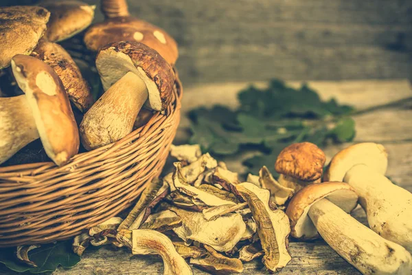 Сушеные грибы и свежесобранный гриб болетус в корзине на деревенском деревянном фоне — стоковое фото