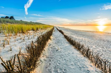 Sandy beach ve günbatımı gökyüzü beyaz kum üzerinde parlayan altın güneş ile