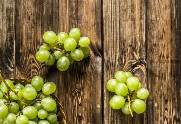 Bunch of green grapes in the basket, autumn fruits on wooden background